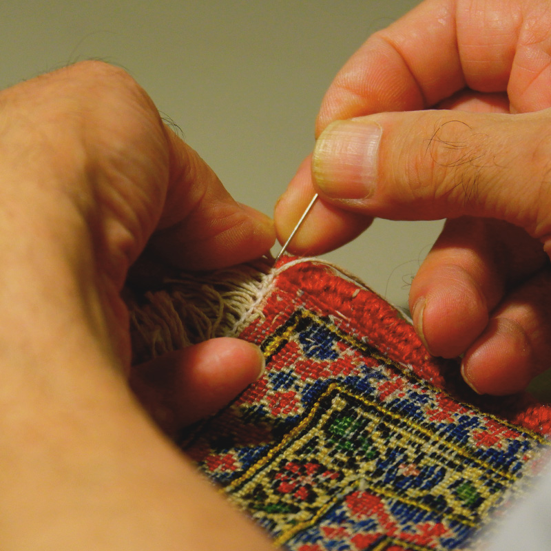 Close up of hands sewing carpet.