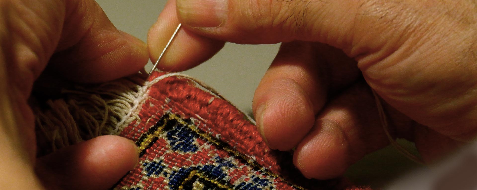 Close up of hands sewing carpet.